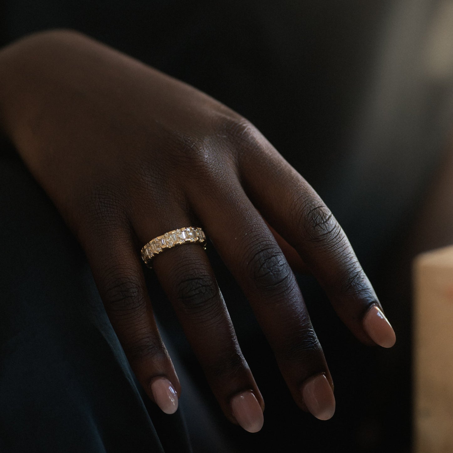 Ellis Mhairi Cameron - Close-up of a hand wearing a gold ring with a dark background