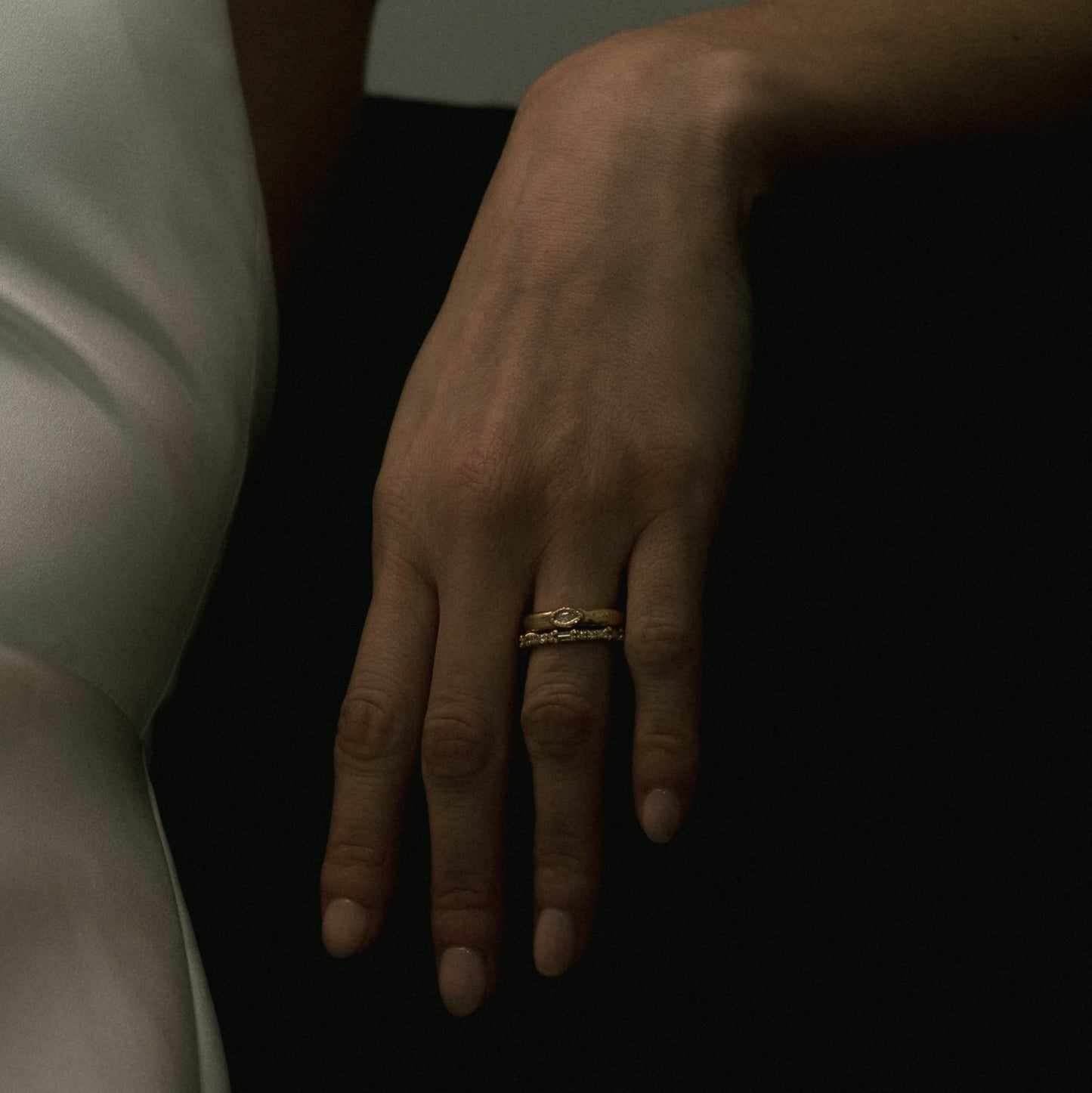 Ellis Mhairi Cameron - Hand wearing a gold ring on a dark background
