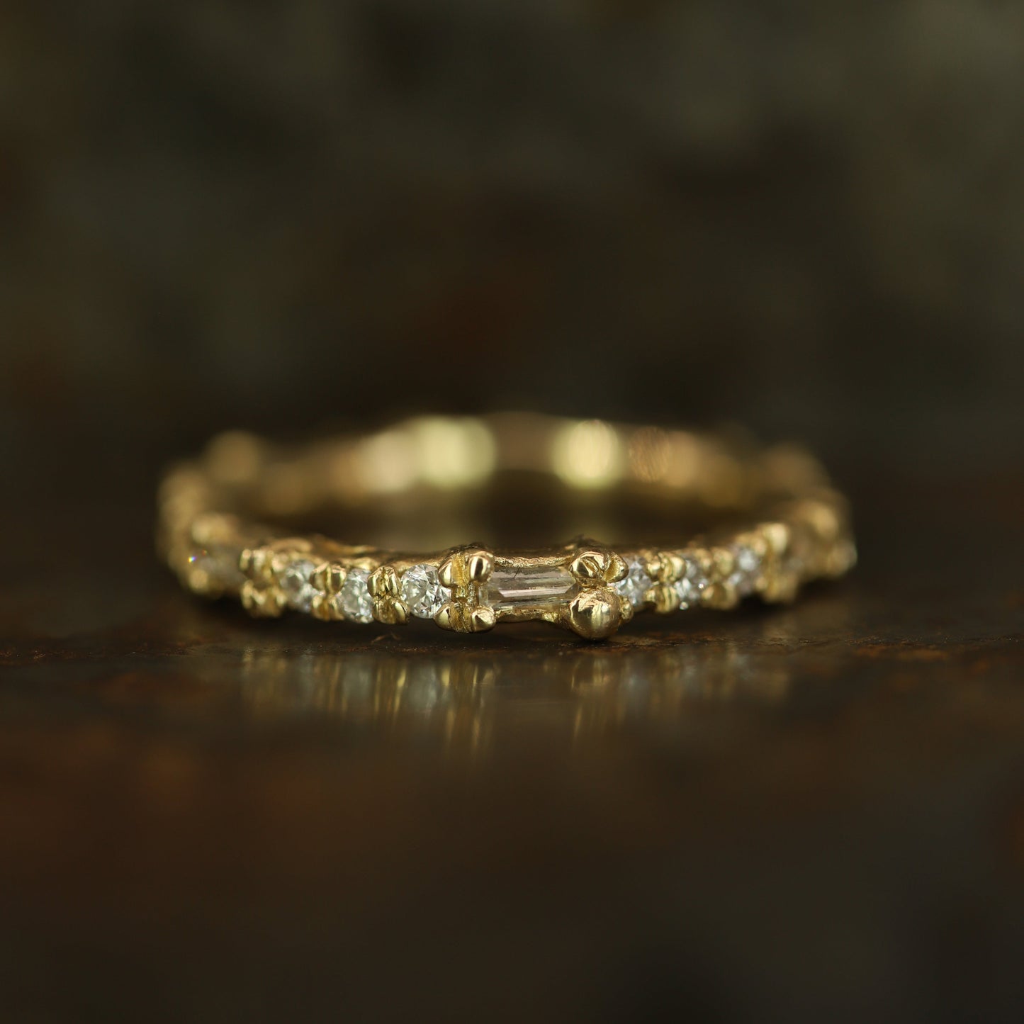 Ellis Mhairi Cameron - Gold ring with small diamonds on a dark wooden surface