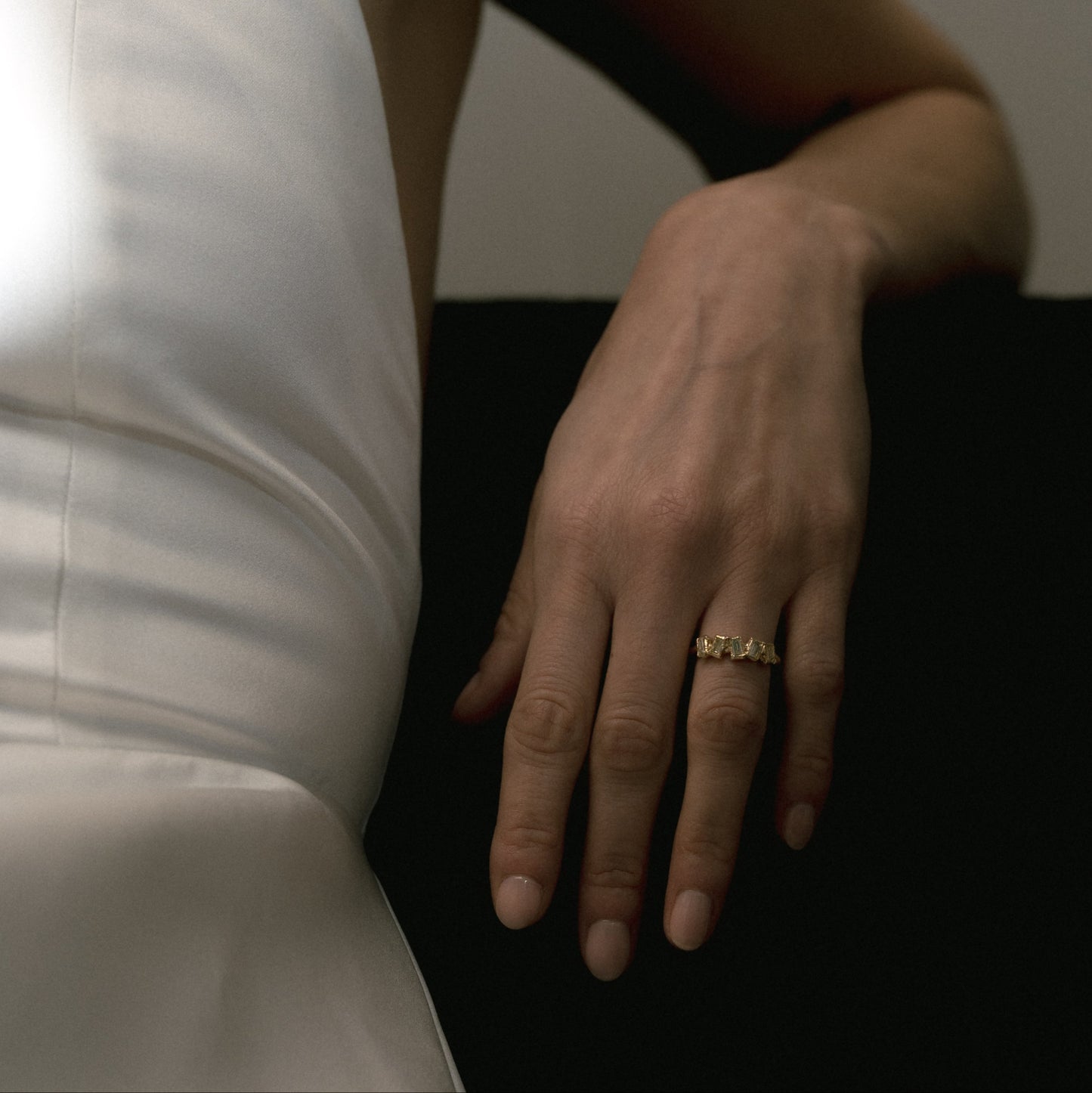 Ellis Mhairi Cameron - Close-up of a hand wearing a gold ring with a plain background