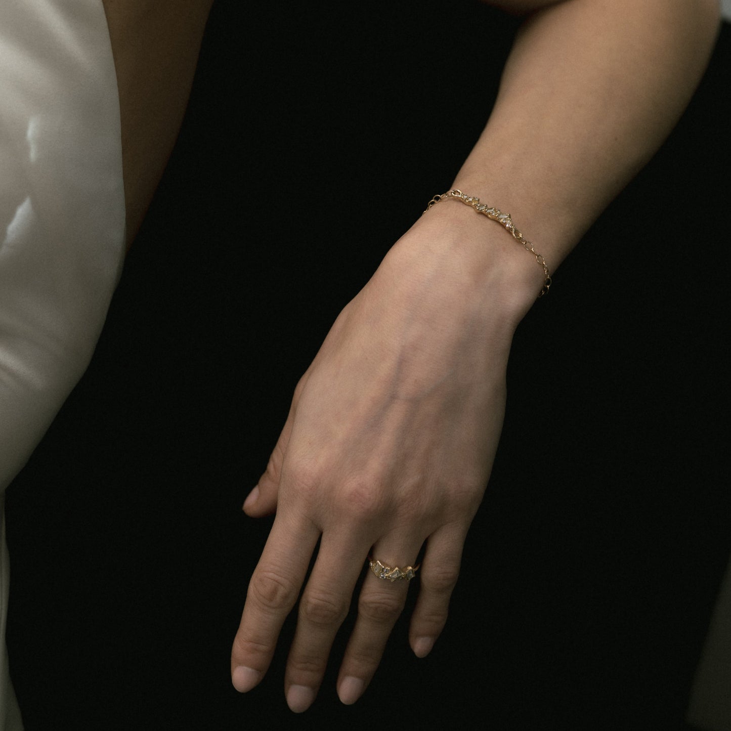Ellis Mhairi Cameron - Hand with gold bracelet and ring on a dark background
