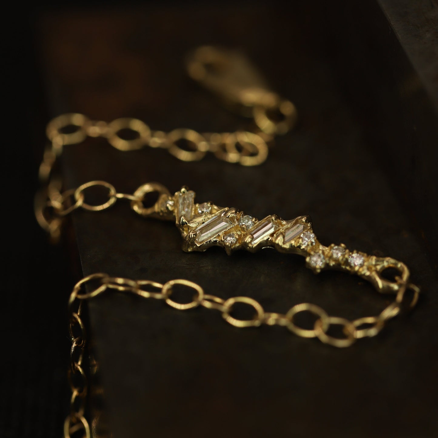 Ellis Mhairi Cameron - Gold bracelet with diamond accents on a dark background