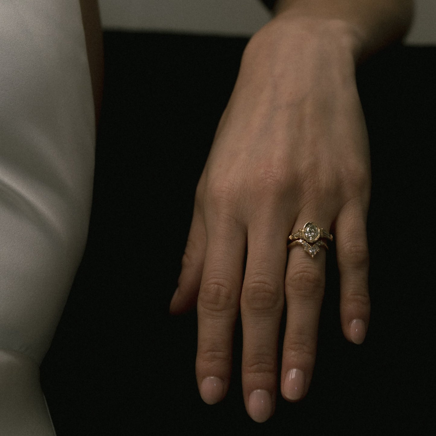 Ellis Mhairi Cameron - Hand wearing a ring on a dark background