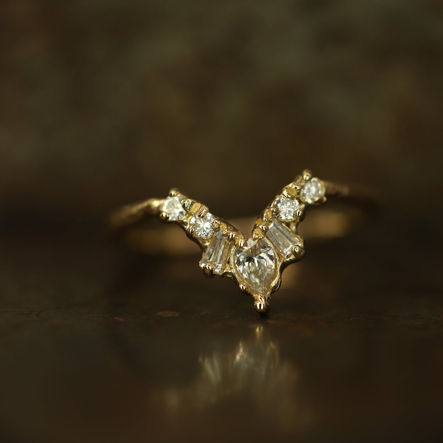 Ellis Mhairi Cameron - Gold ring with diamond accents on a dark background