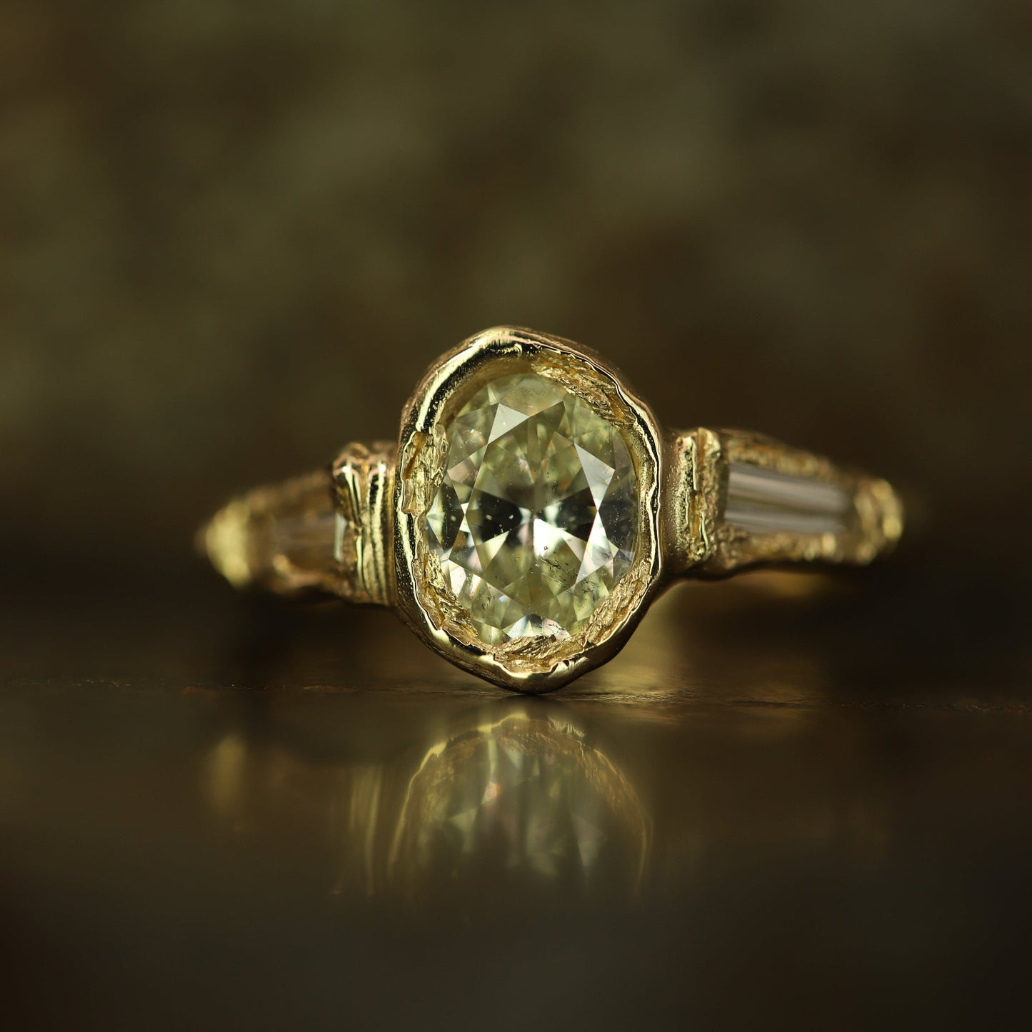 Ellis Mhairi Cameron - Gold ring with a green gemstone on a reflective surface