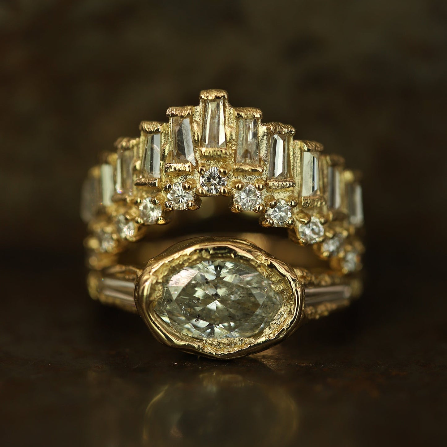 Ellis Mhairi Cameron - Gold ring with a large central diamond and smaller baguette-cut diamonds on a dark background