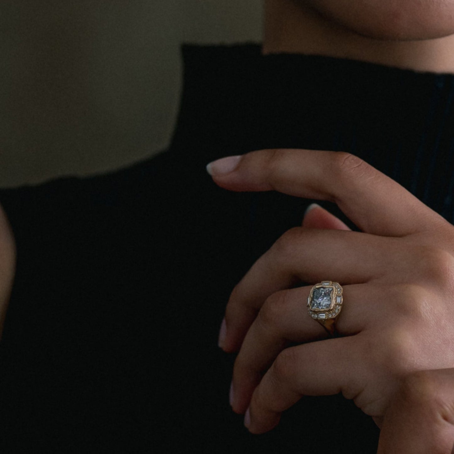 Ellis Mhairi Cameron - Close-up of a hand wearing a ring with a large diamond on a dark background