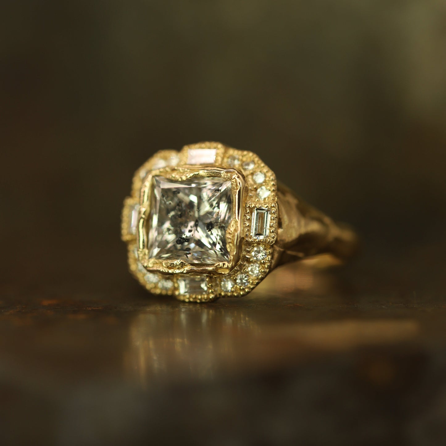 Ellis Mhairi Cameron - Gold ring with a large diamond and smaller diamonds on a dark background