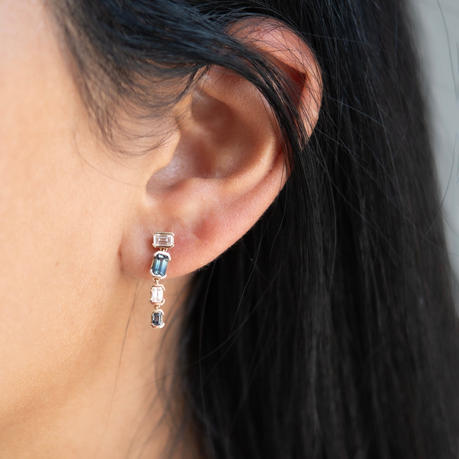 Close-up of an ear wearing a set of earrings with dark hair.
