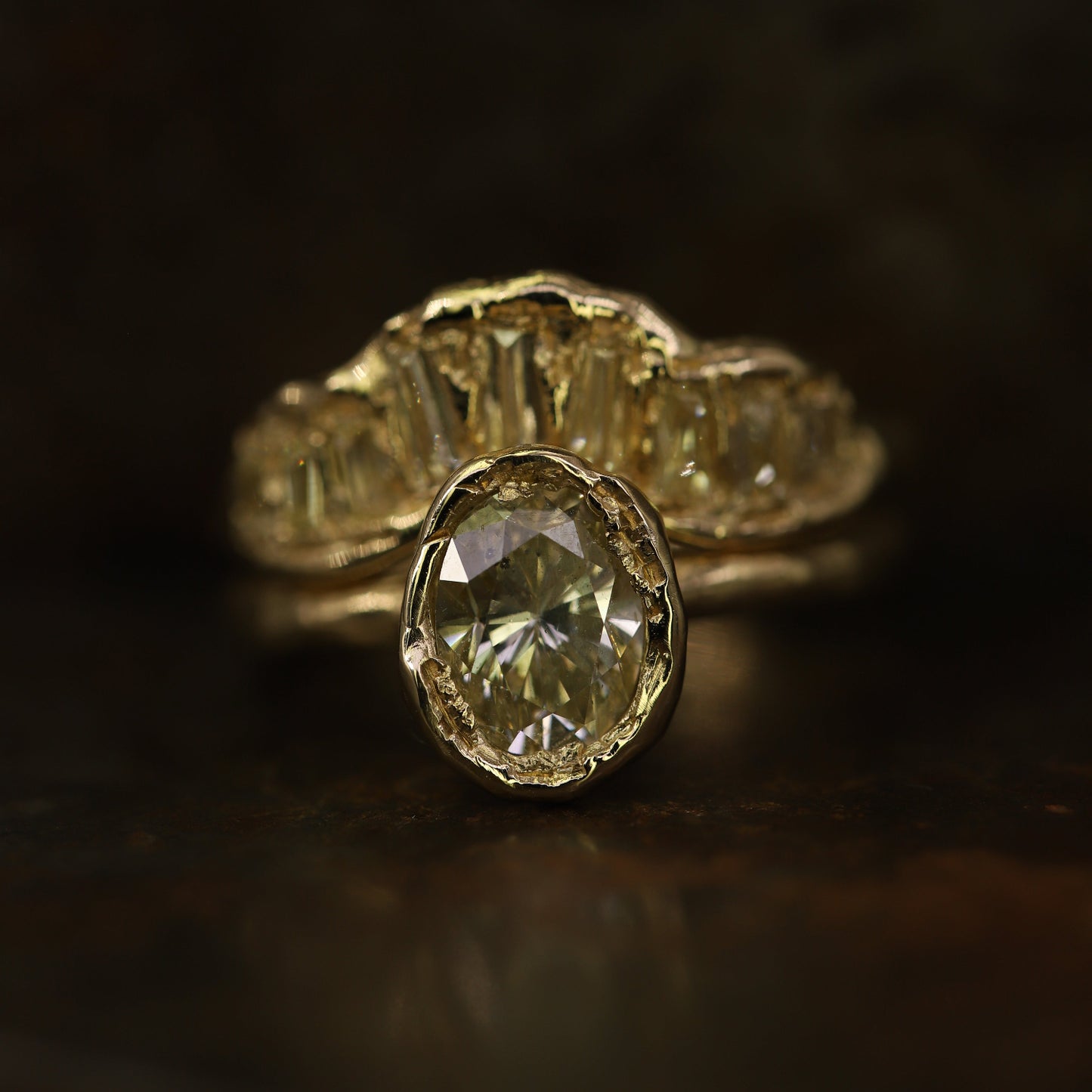Ellis Mhairi Cameron - Gold ring with a large diamond and smaller diamonds on a dark background