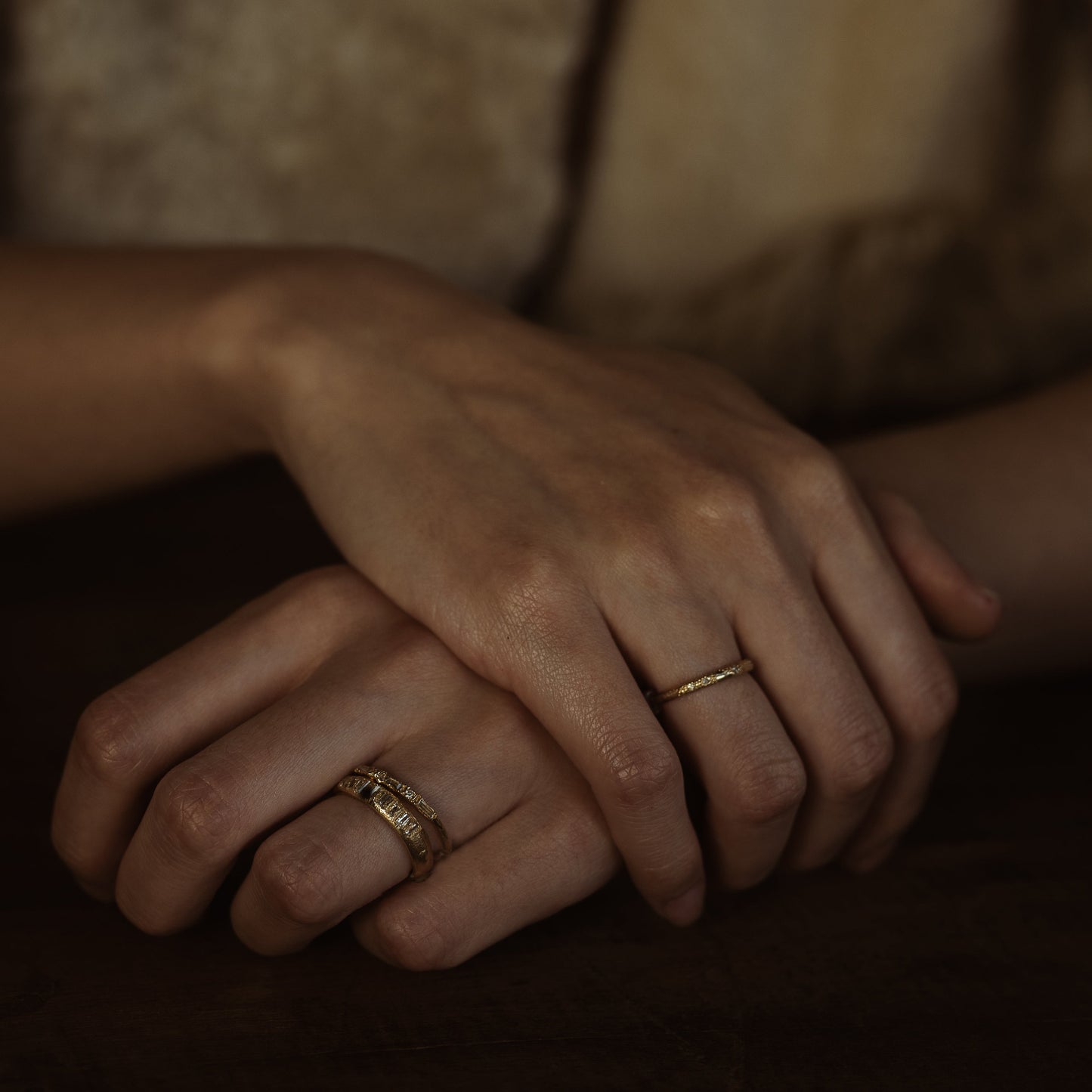 Ellis Mhairi Cameron - Close-up of hands with gold rings on a dark background
