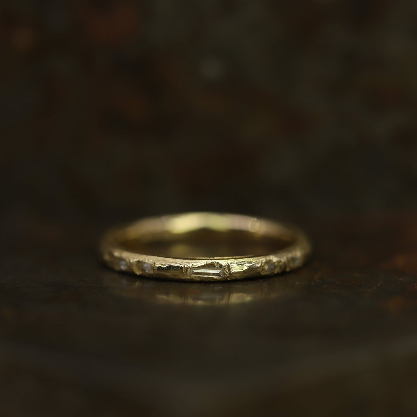 Ellis Mhairi Cameron - Gold ring with a textured surface on a dark background