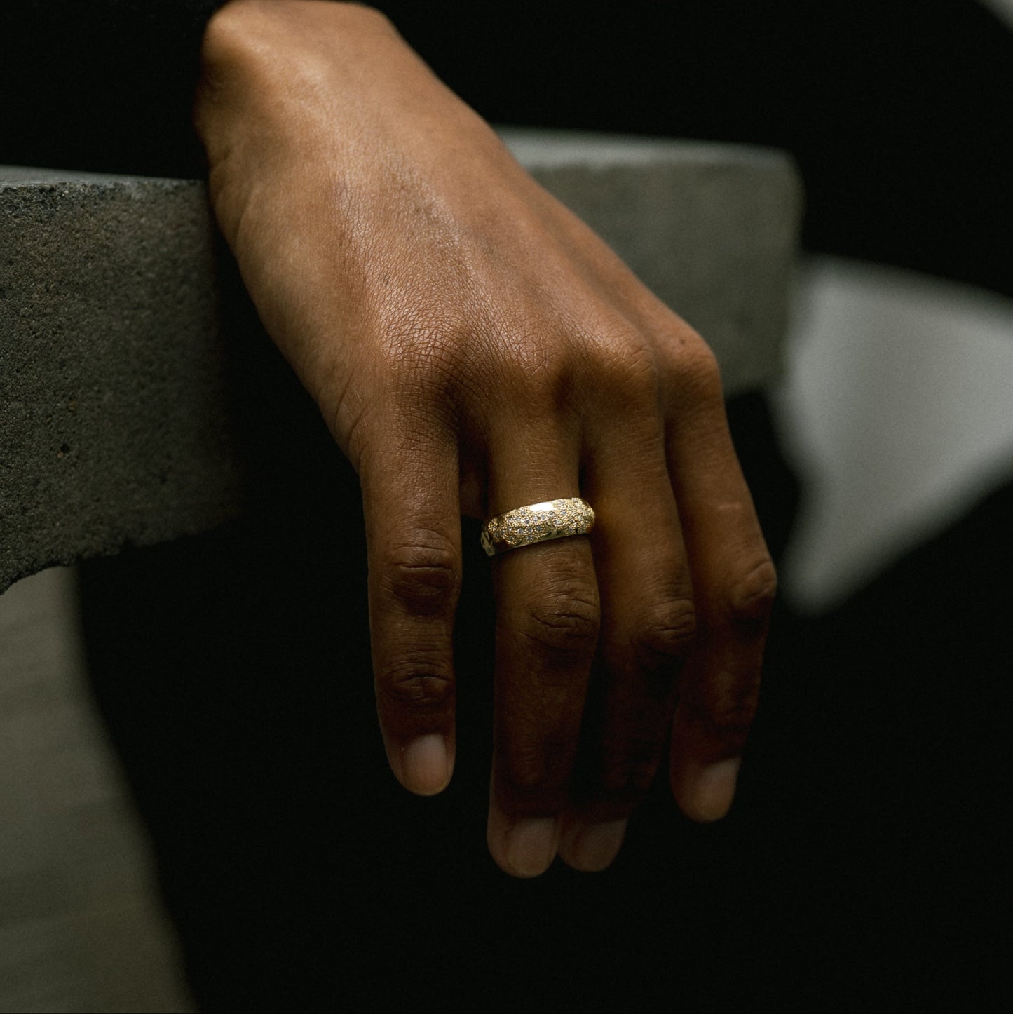 Ellis Mhairi Cameron - Hand wearing a gold ring on a dark background