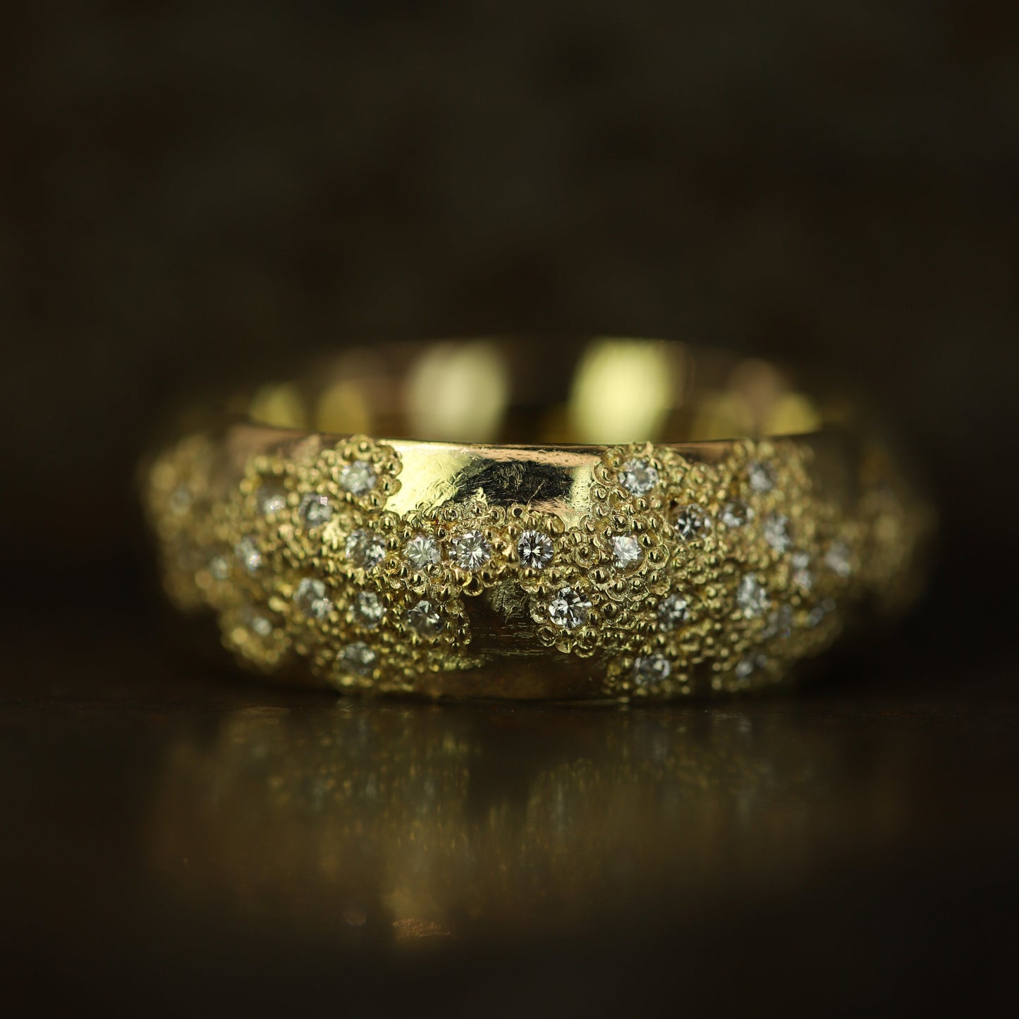 Ellis Mhairi Cameron - Gold ring with textured band and embedded stones on a dark background