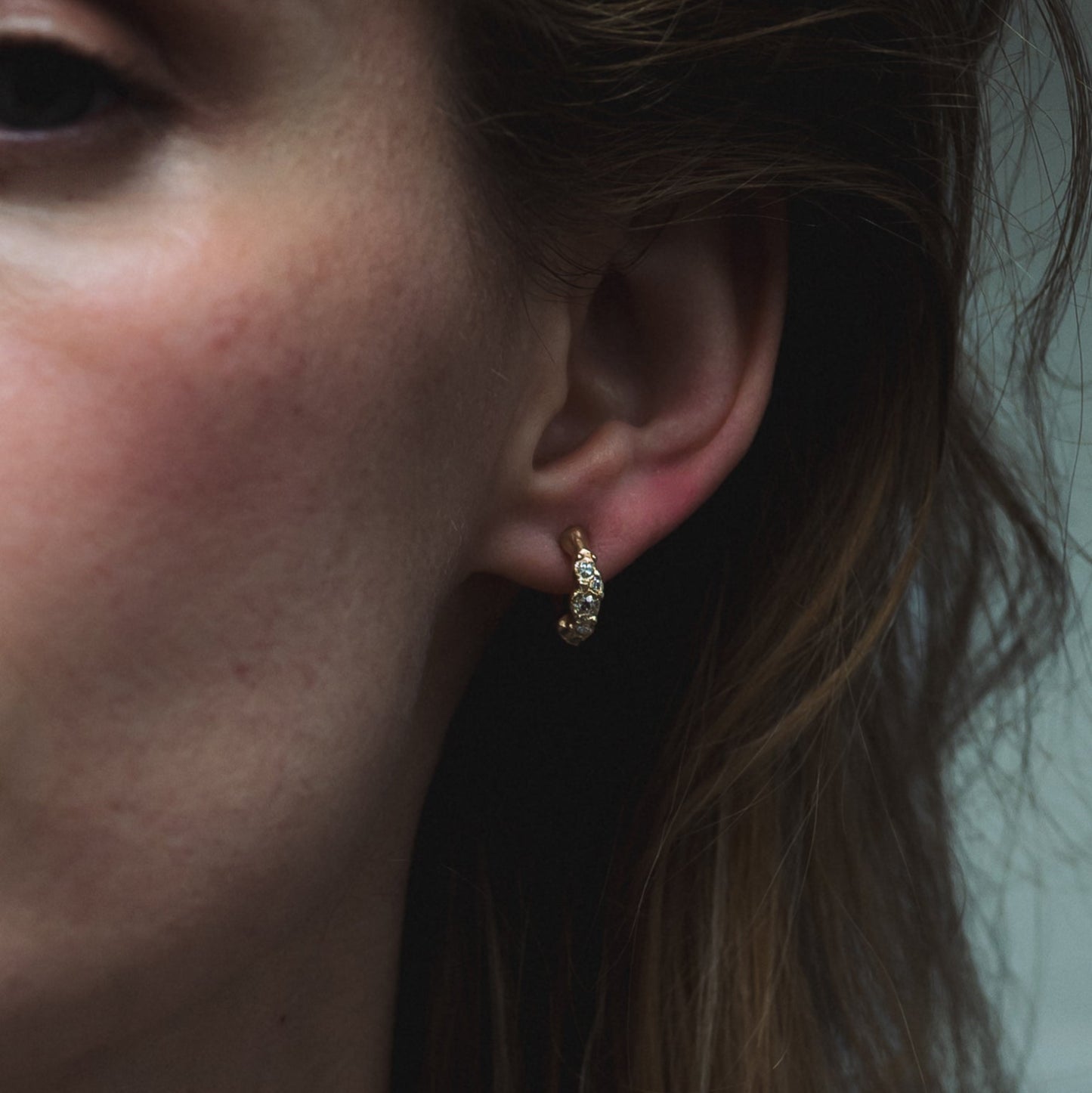 Ellis Mhairi Cameron - Close-up of an ear wearing a gold earring with a blurred background