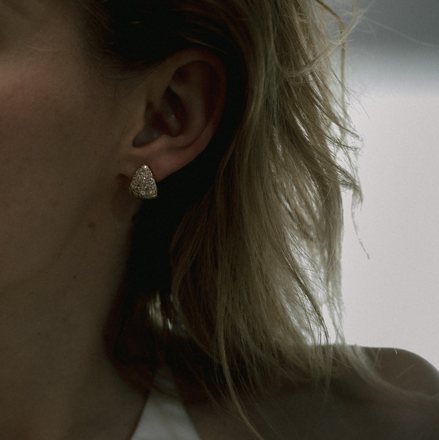 Ellis Mhairi Cameron - Close-up of an ear wearing a gold earring with blurred background