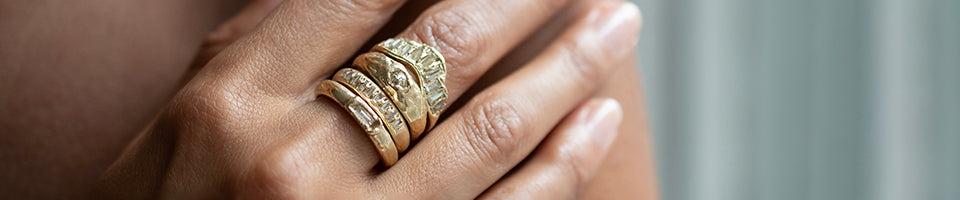 four textured gold and diamond rings shown on hand model