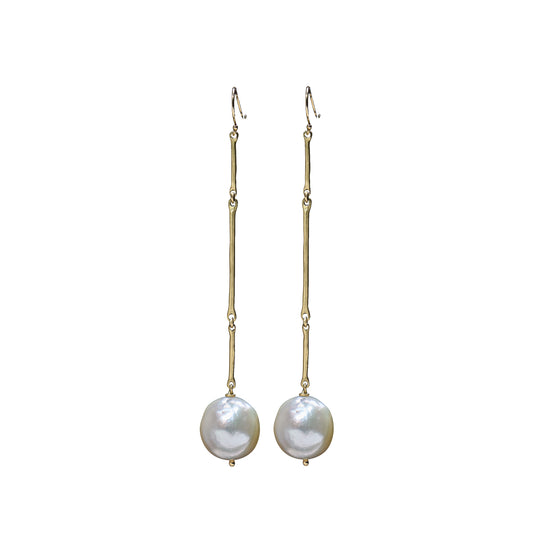 A pair of gold drop earrings with a textured vertical bar, a small bead, and a round white baroque pearl hanging from the end, shown against a plain white background.