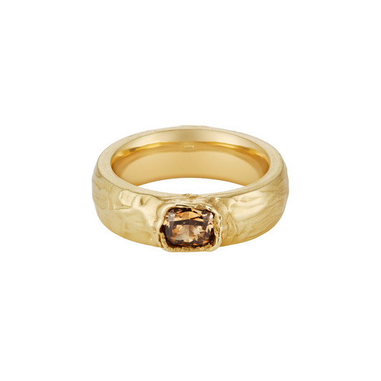 A textured yellow gold ring featuring a central cushion-cut brown gemstone, shown on a plain white background.