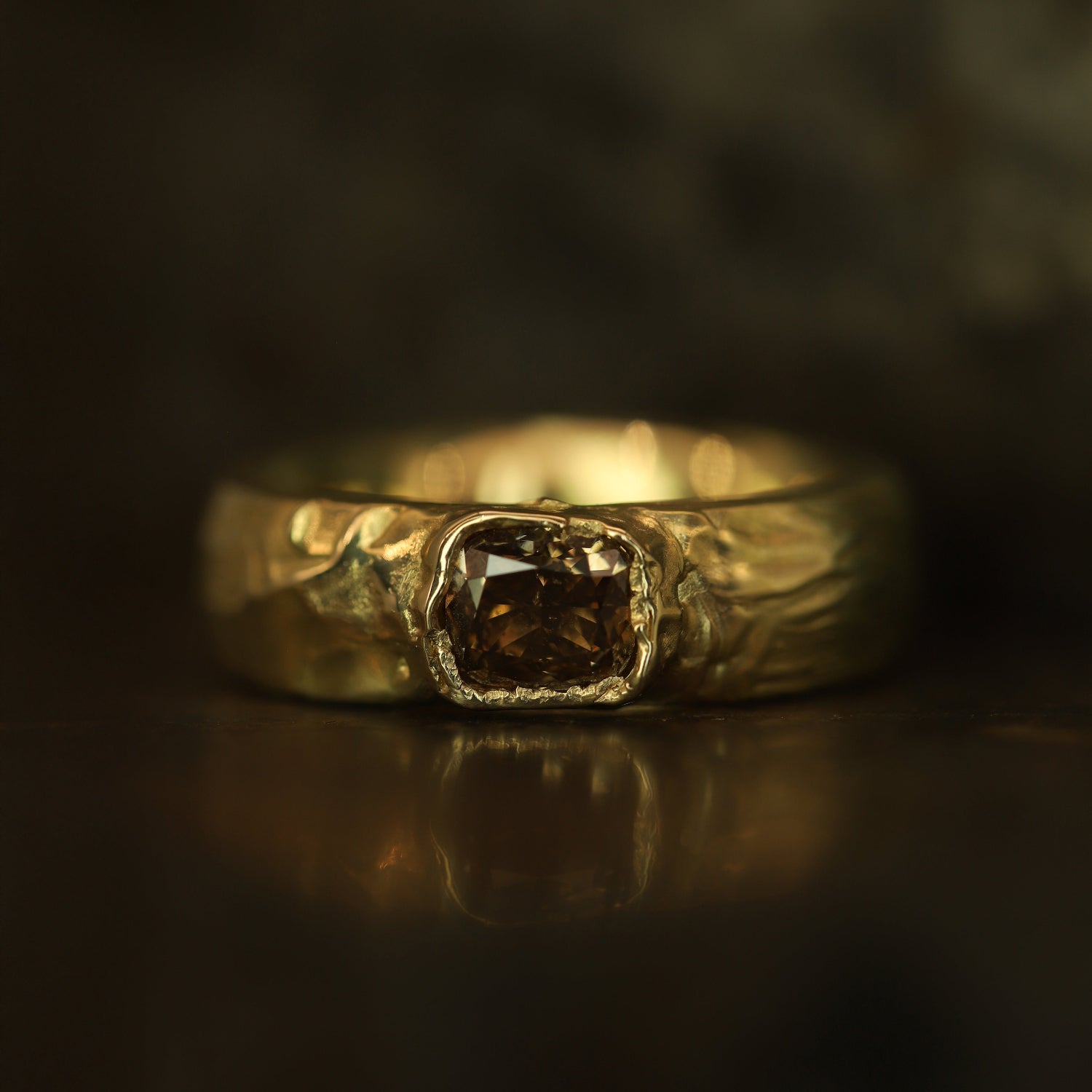Gold ring with a central diamond on a dark background