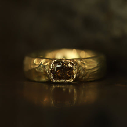 Gold ring with a central diamond on a dark background