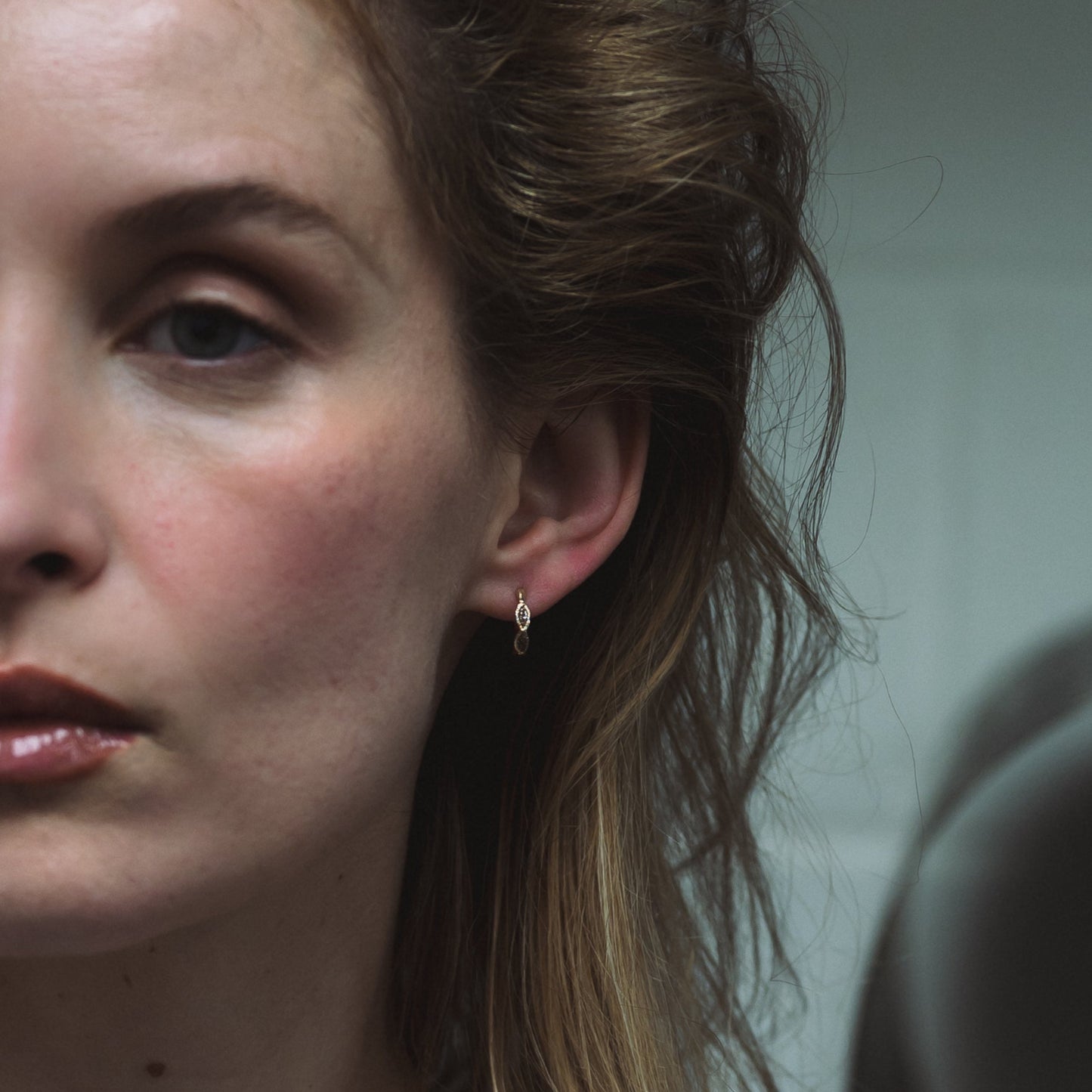 Ellis Mhairi Cameron - Close-up of a woman's face with an earring, blurred background