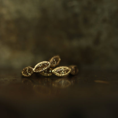 Ellis Mhairi Cameron - Gold earrings on a dark surface with a blurred background