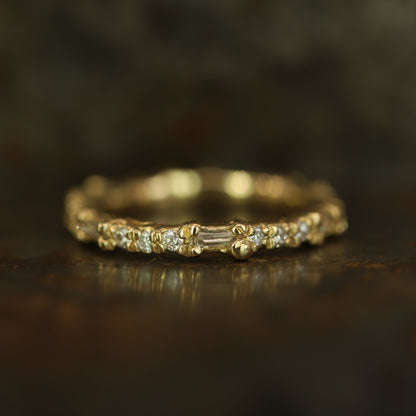 Ellis Mhairi Cameron - Gold ring with small diamonds on a dark wooden surface