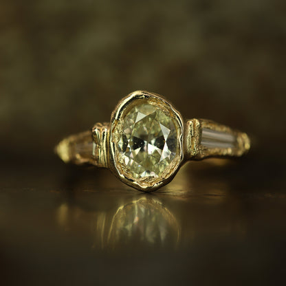 Ellis Mhairi Cameron - Gold ring with a green gemstone on a reflective surface