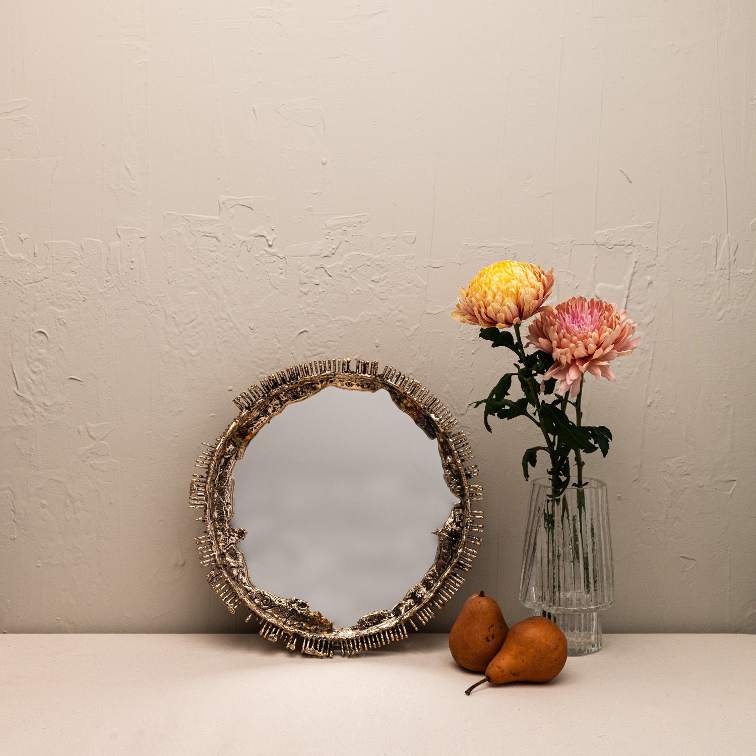 Decorative mirror with a vase of flowers and pears on a neutral background