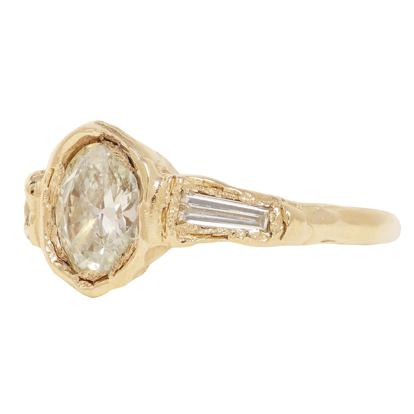 A yellow gold ring featuring a large oval-cut clear center stone and two baguette-cut side stones, shown on a plain white background.