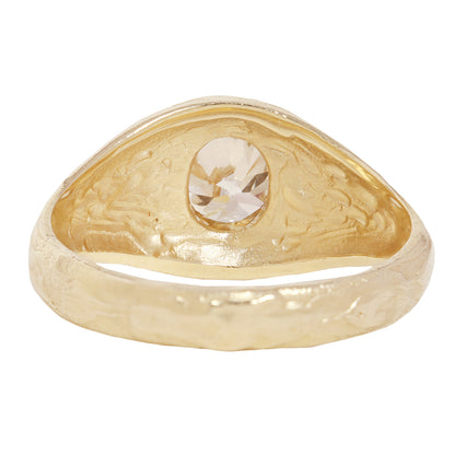 A textured gold signet-style ring featuring a large, round brilliant-cut diamond center stone, shown against a plain white background.