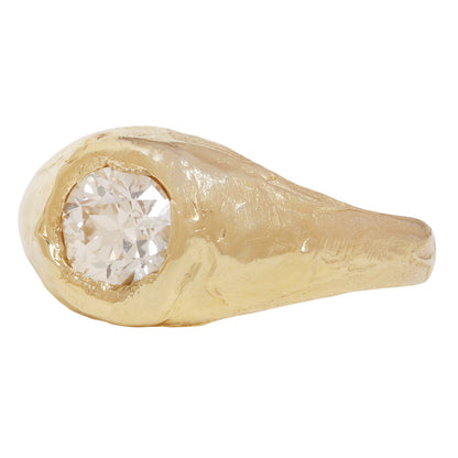 A textured gold signet-style ring featuring a large, round brilliant-cut diamond center stone, shown against a plain white background.