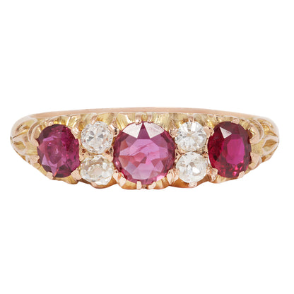 Gold ring with pink and red gemstones on a white background