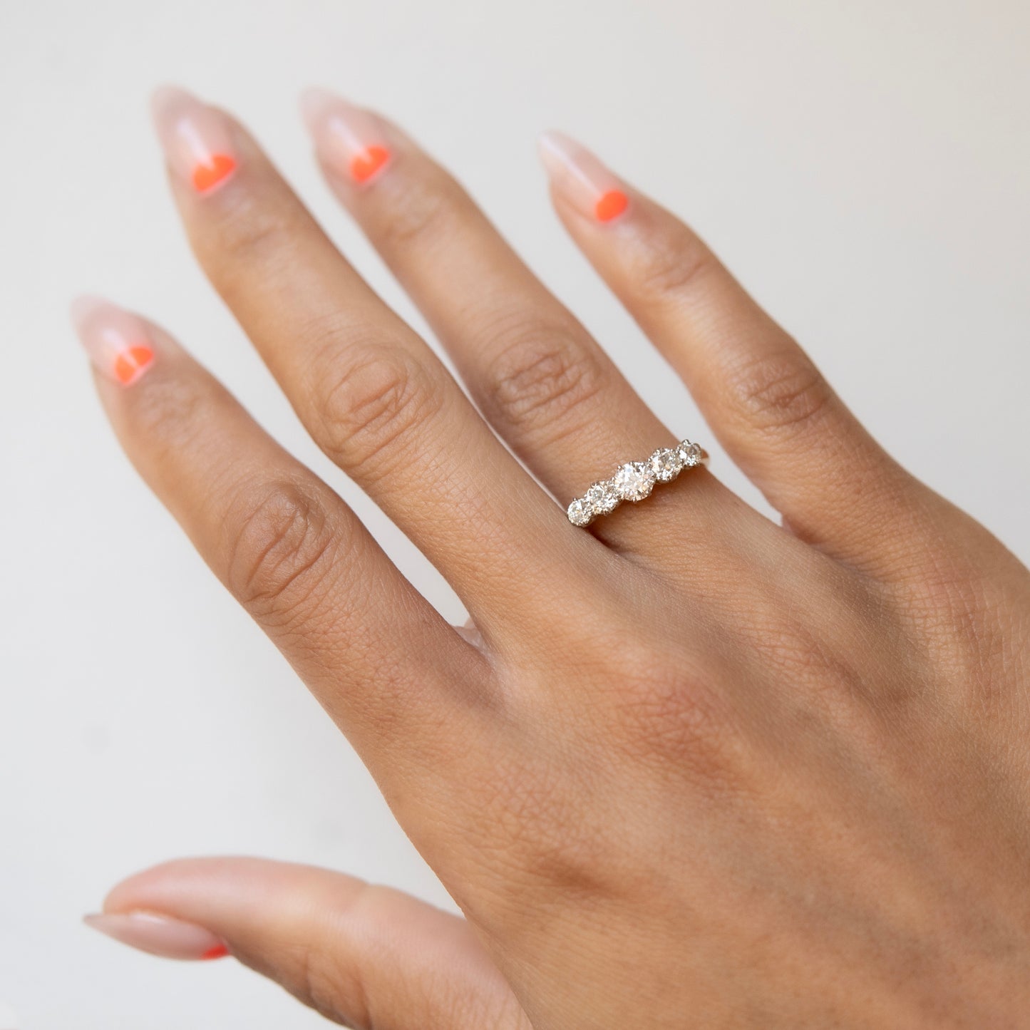 Hand wearing a diamond ring with a neutral background