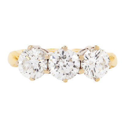 Gold ring with three clear gemstones on a white background