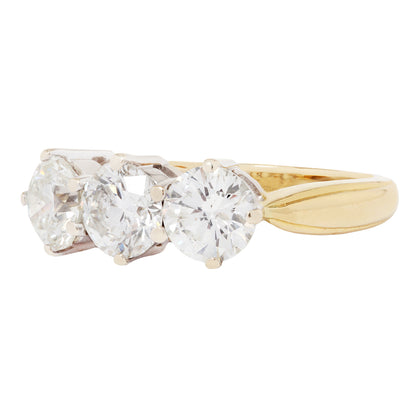 Gold ring with three clear gemstones on a white background