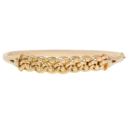 A gold bangle bracelet featuring a raised, textured chain-link pattern across the front, set against a plain white background.