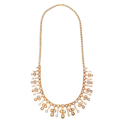 A gold statement necklace featuring a delicate chain, a wide collar of small round pearls, and multiple dangling floral and leaf motifs embellished with pesrls, shown against a plain white background.