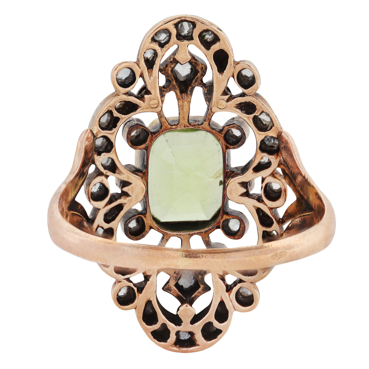 A rose gold filigree ring featuring a central green peridot gemstone and small dark gemstone accents, shown on a plain white background.