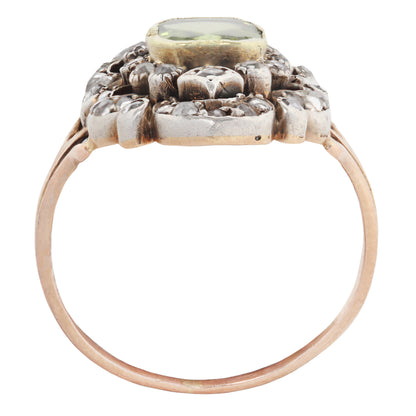 An antique-style ring featuring a rose gold band, a silver-toned floral cluster setting, and a central oval green gemstone, shown against a plain white background.