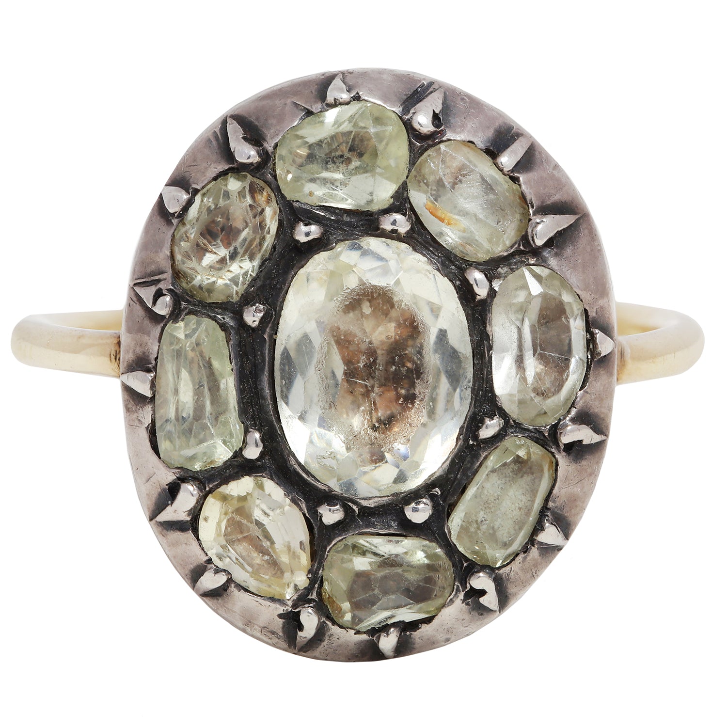Antique ring with central gemstone and smaller green stones on a white background