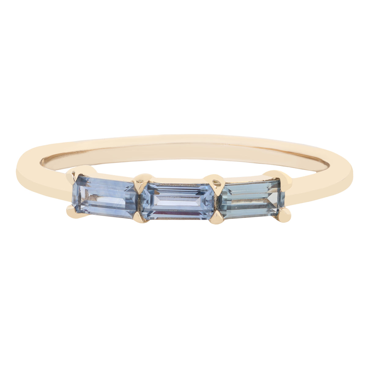 A yellow gold ring featuring three baguette-cut light blue gemstones in a prong setting, shown against a plain white background.