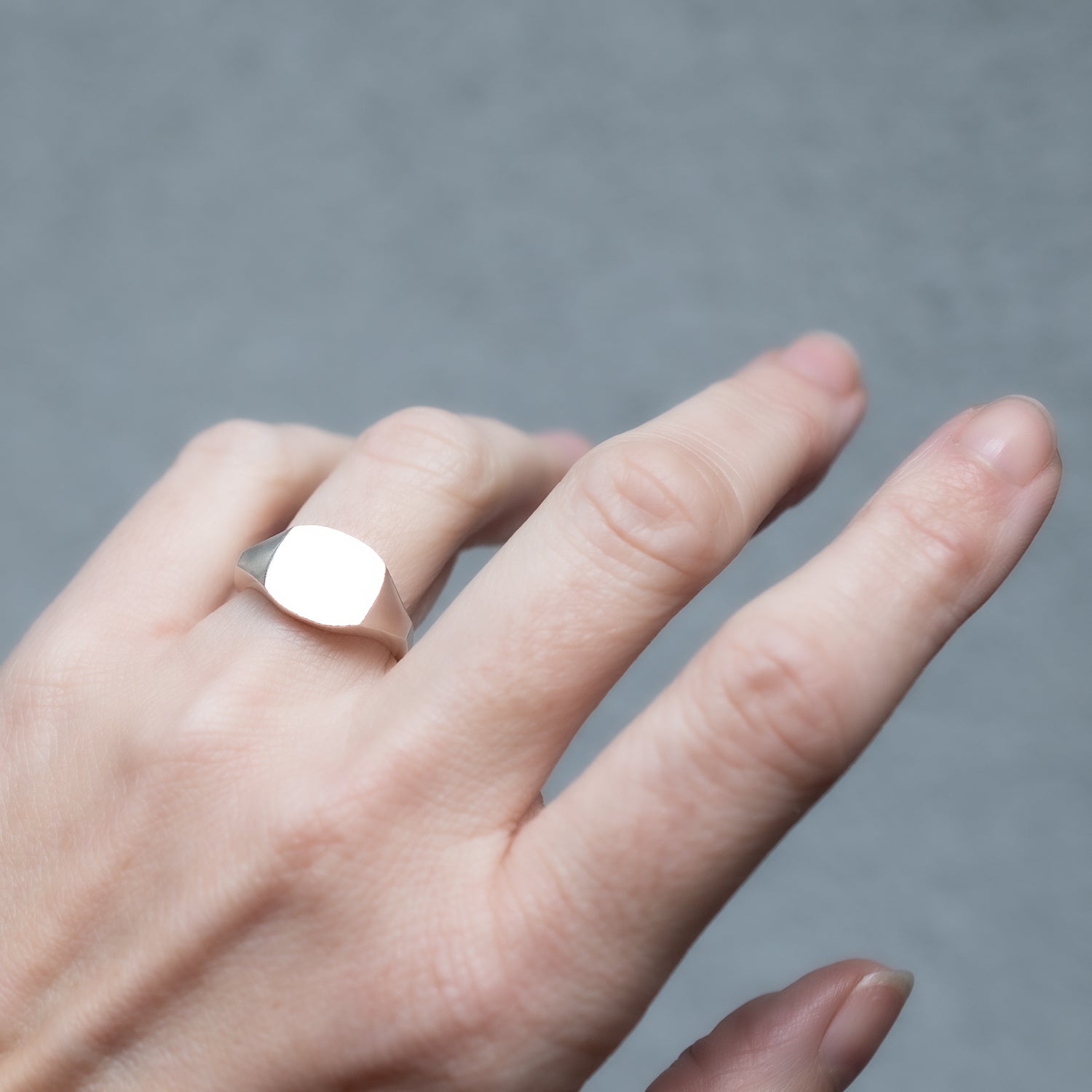 Silver square ring on a hand.