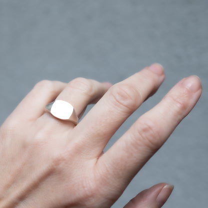Silver square ring on a hand.