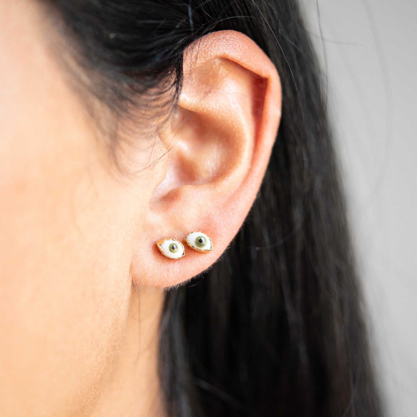 Close-up of an ear wearing small earrings with a neutral background