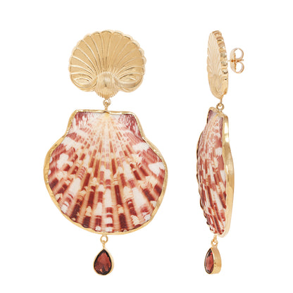 A pair of gold-toned dangle earrings featuring a large scallop shell motif with pink and cream striped detailing, a smaller scallop above it, and a small teardrop-shaped red gemstone dangling below each earring, shown on a plain white background.