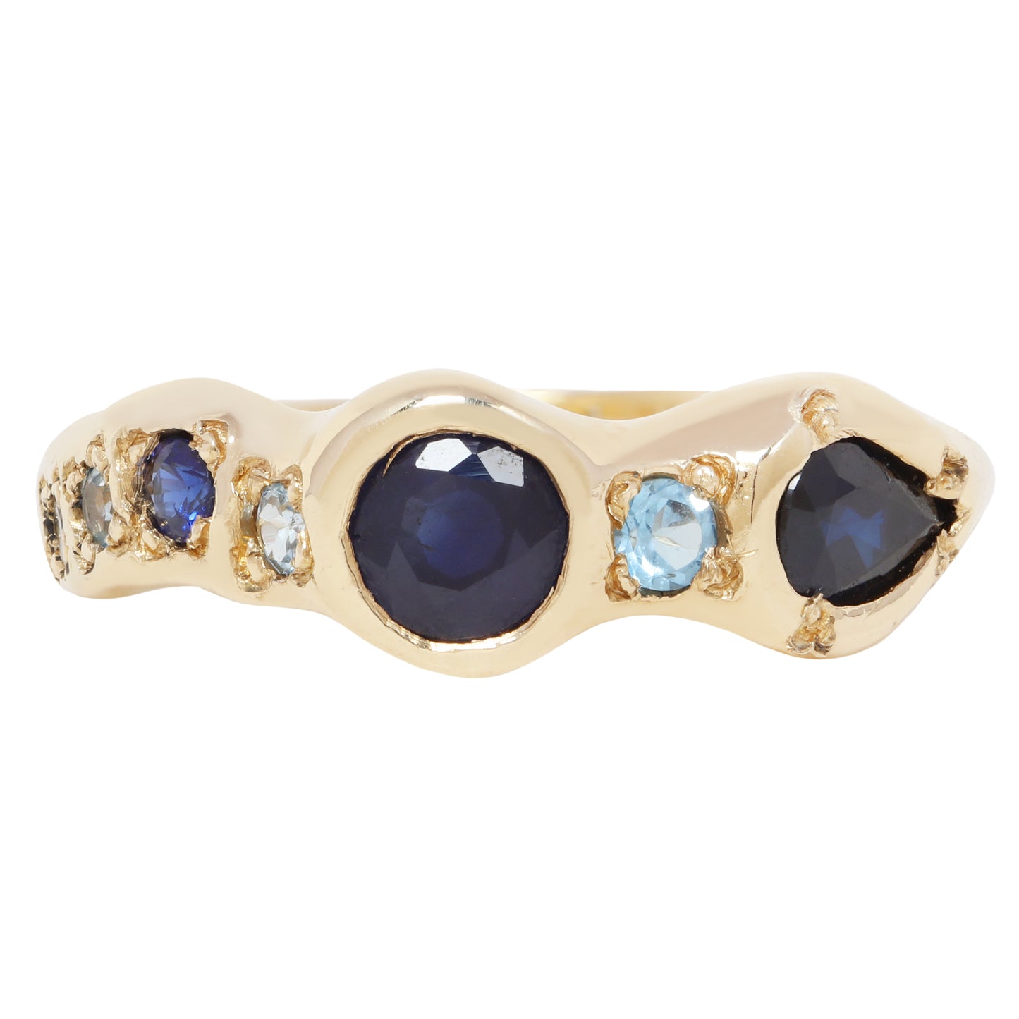 A gold ring featuring a wavy channel setting with a large oval dark blue sapphire in the center, flanked by smaller round blue and light blue round-cut gemstones, set against a plain white background.