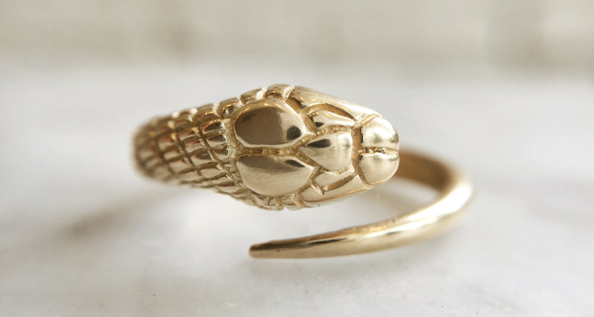 Gold snake-shaped ring on a light background