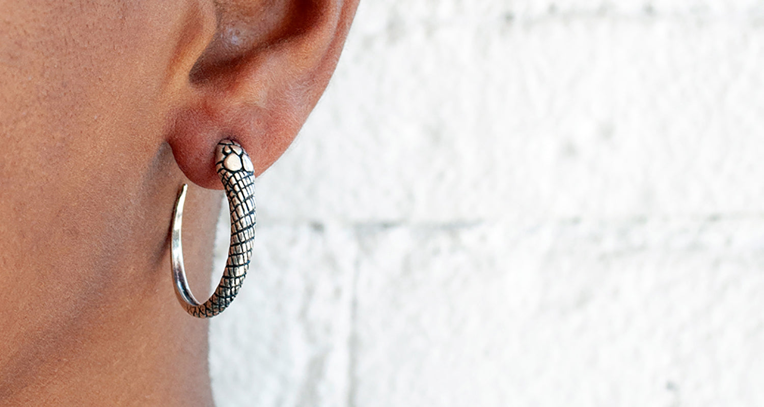 Silver hoop earring worn by a person with a light background